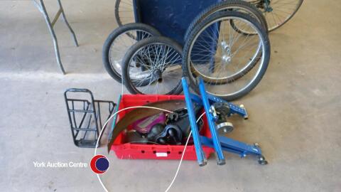 Box of various bicycle parts and wheels and bicycle trainer